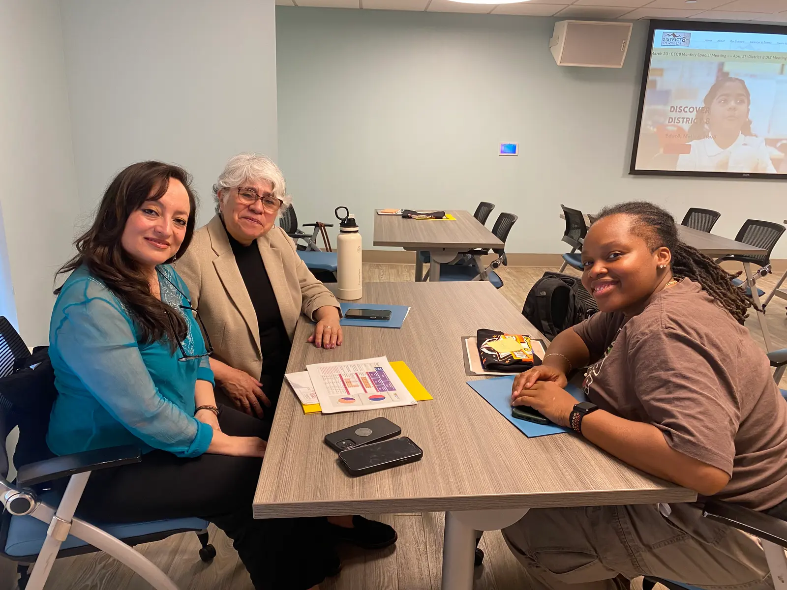 Three community members meeting at a District 8 conference table