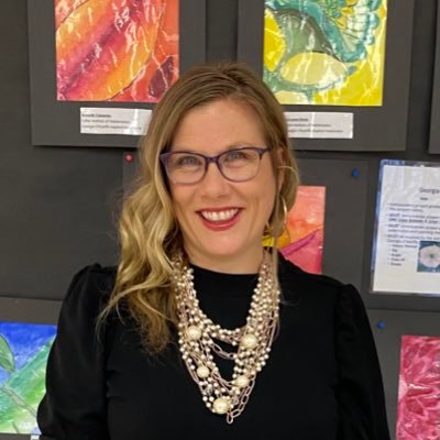 Jennifer Joynt smiling in front of student artwork display