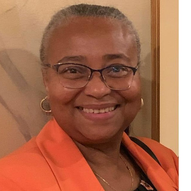 Ellen Johnson smiling in an orange blazer and glasses