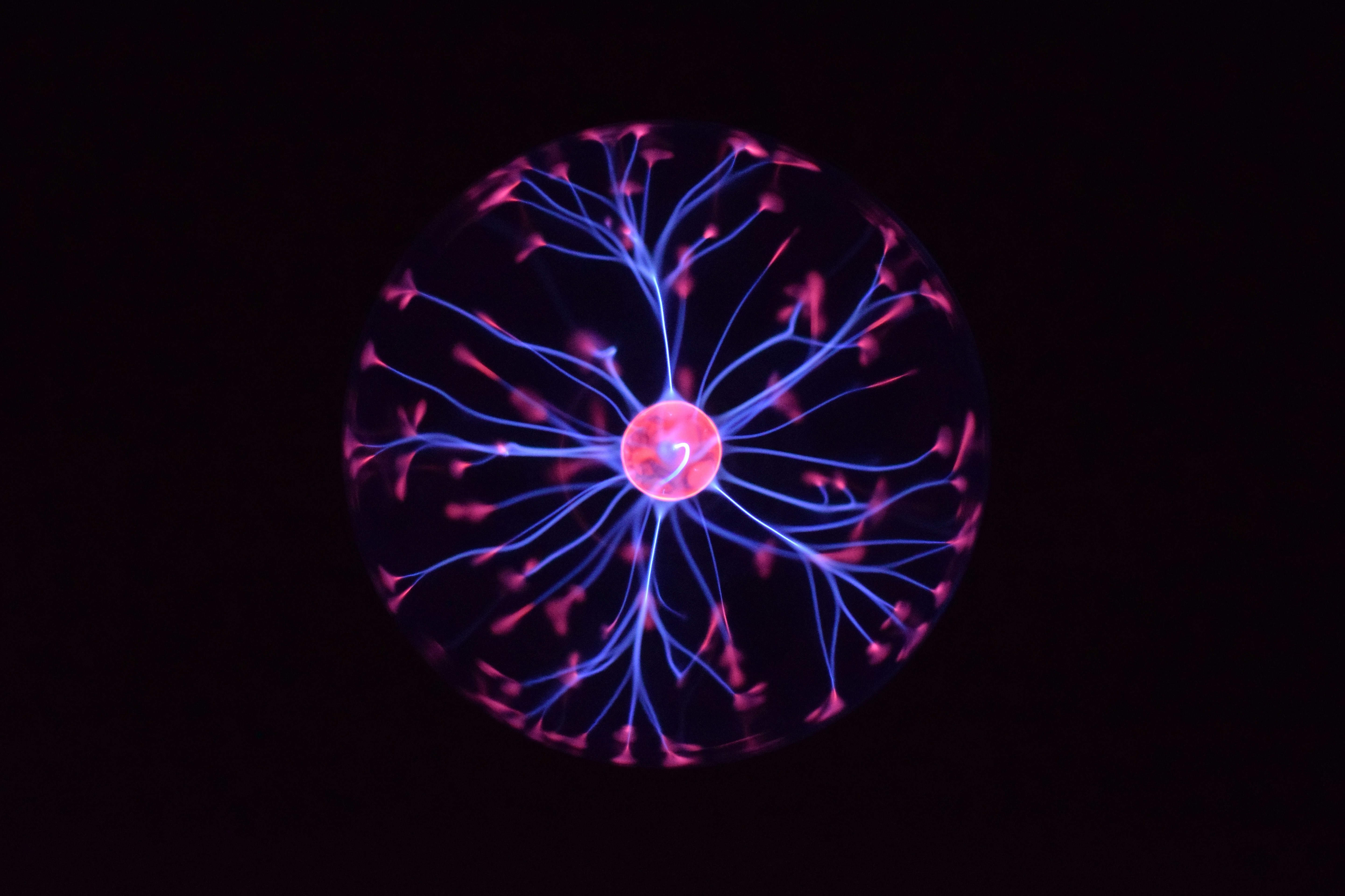 Glowing plasma globe with branching pink and blue filaments in the dark