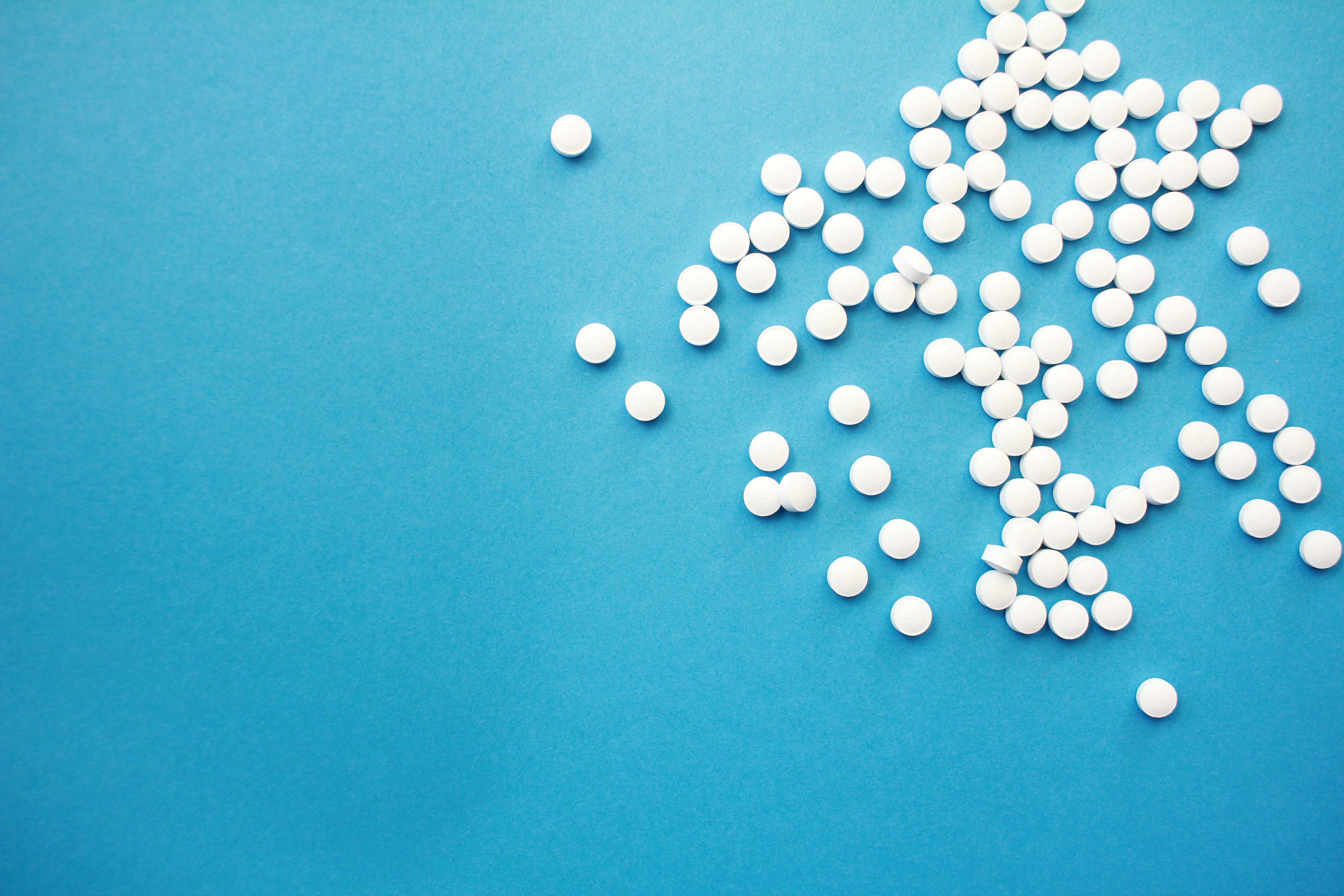 Scattered white pills on a bright blue background with open copy space