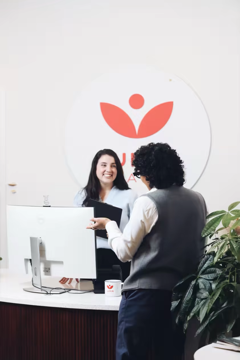 Receptionist handing enrollment paperwork to a patient at the front desk