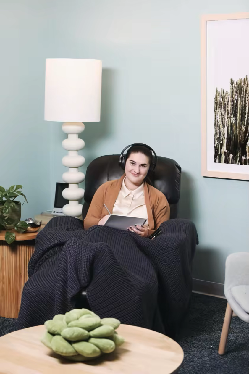 Patient journaling in a recliner with headphones during a session