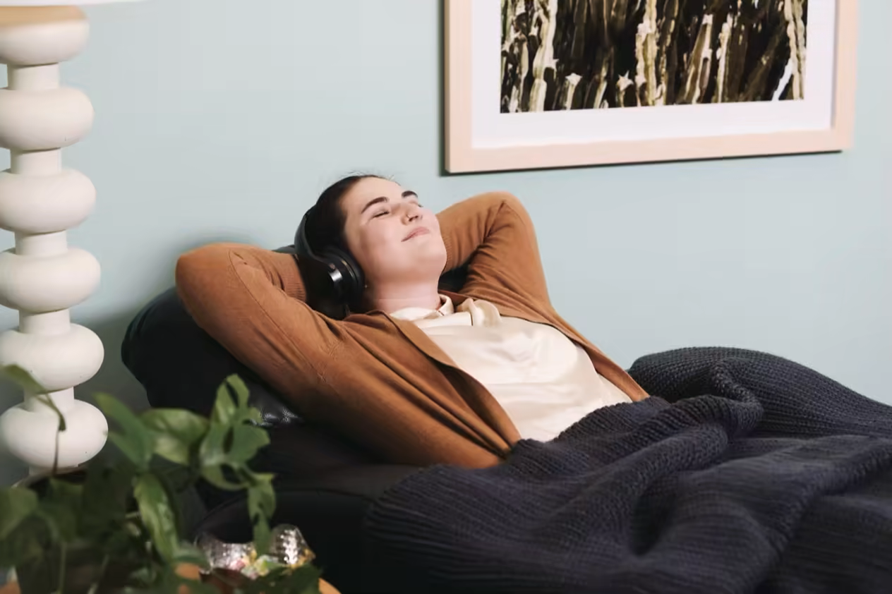 Patient resting peacefully with headphones under a knit blanket