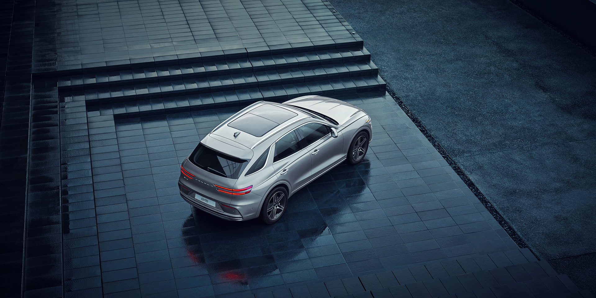 Above three quarter side view of white Electrified GV70 charging on street