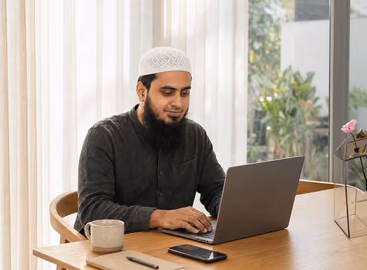Bearded professional working on a laptop at a home desk
