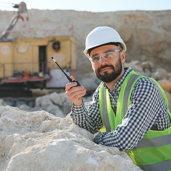 Trabajador en mina atento y sujetando un radio.
