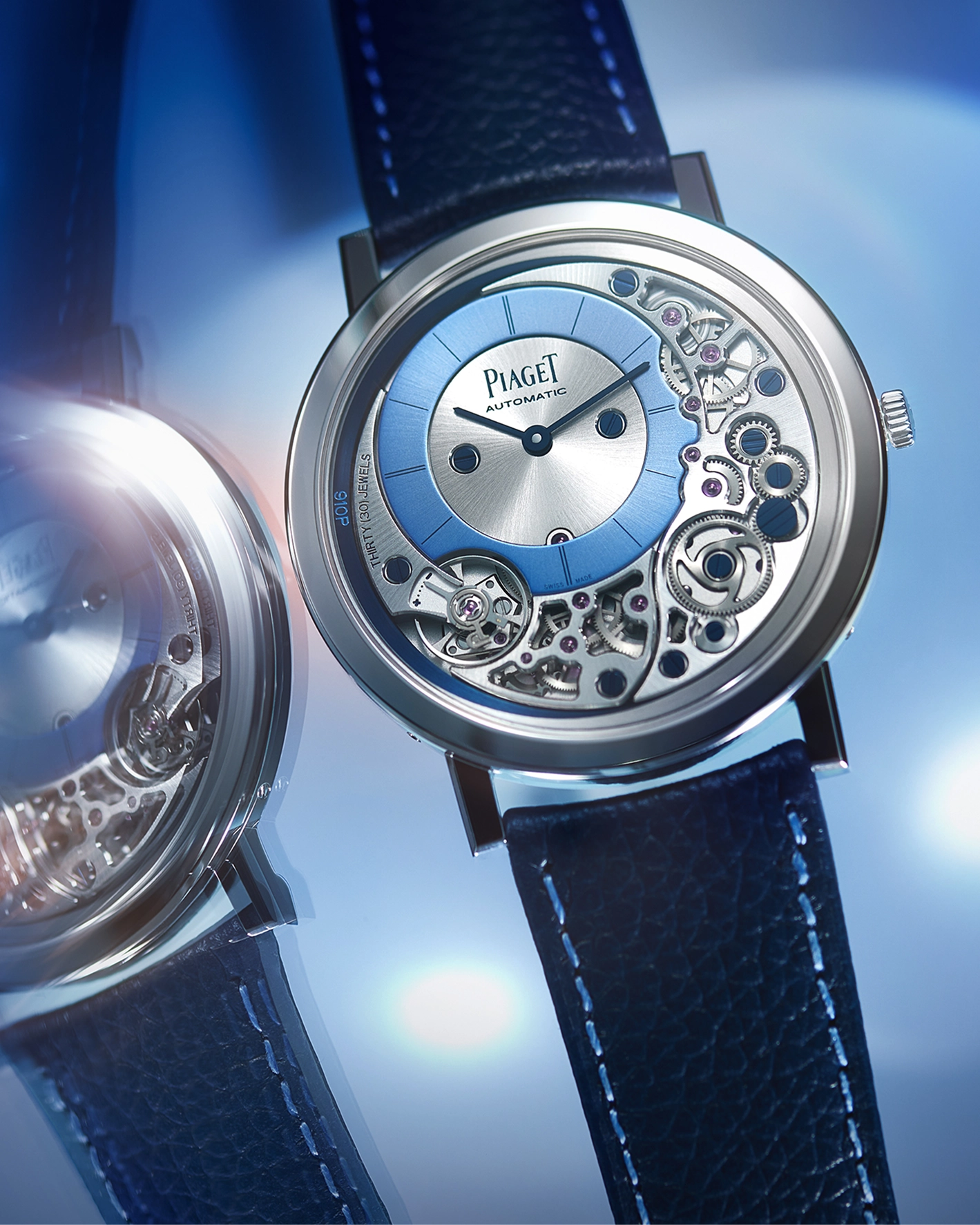 The Piaget Altiplano 910P with a skeletonised movement, blue sunray dial and navy leather strap, shown alongside its caseback against a blue atmospheric background.