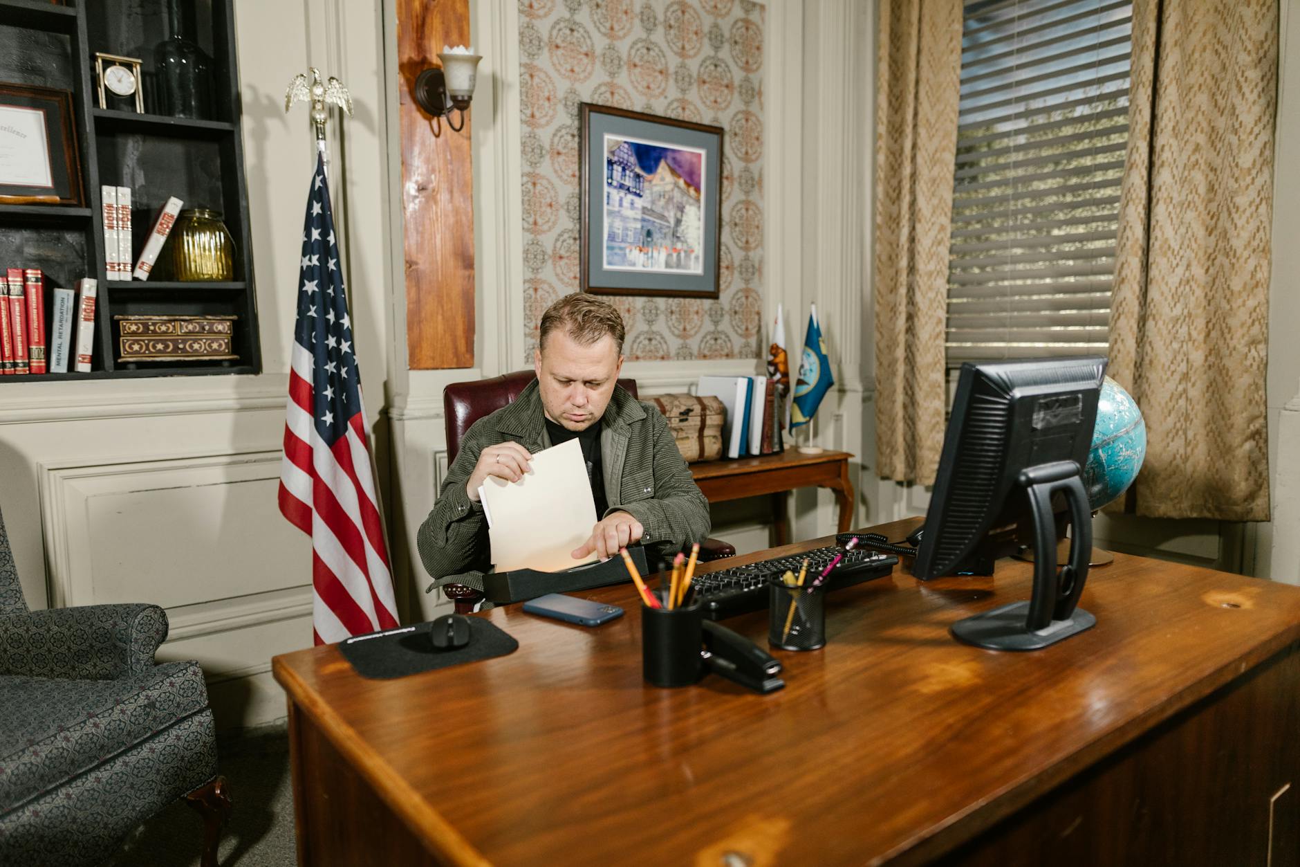 A lawyer in an office reviewing legal documents at a desk with an American flag nearby.