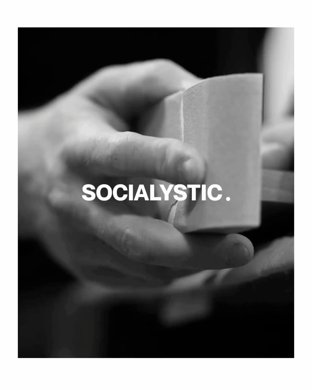 Close-up of a hand holding a rectangular block with the text SOCIALYSTIC overlayed.