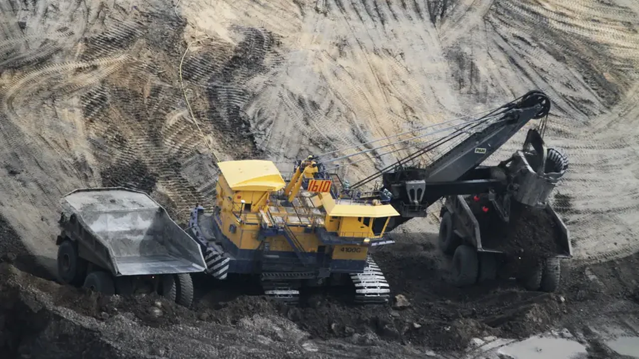 A large excavator and dump trucks actively working at a mining site, showcasing the use of heavy equipment in operational settings.