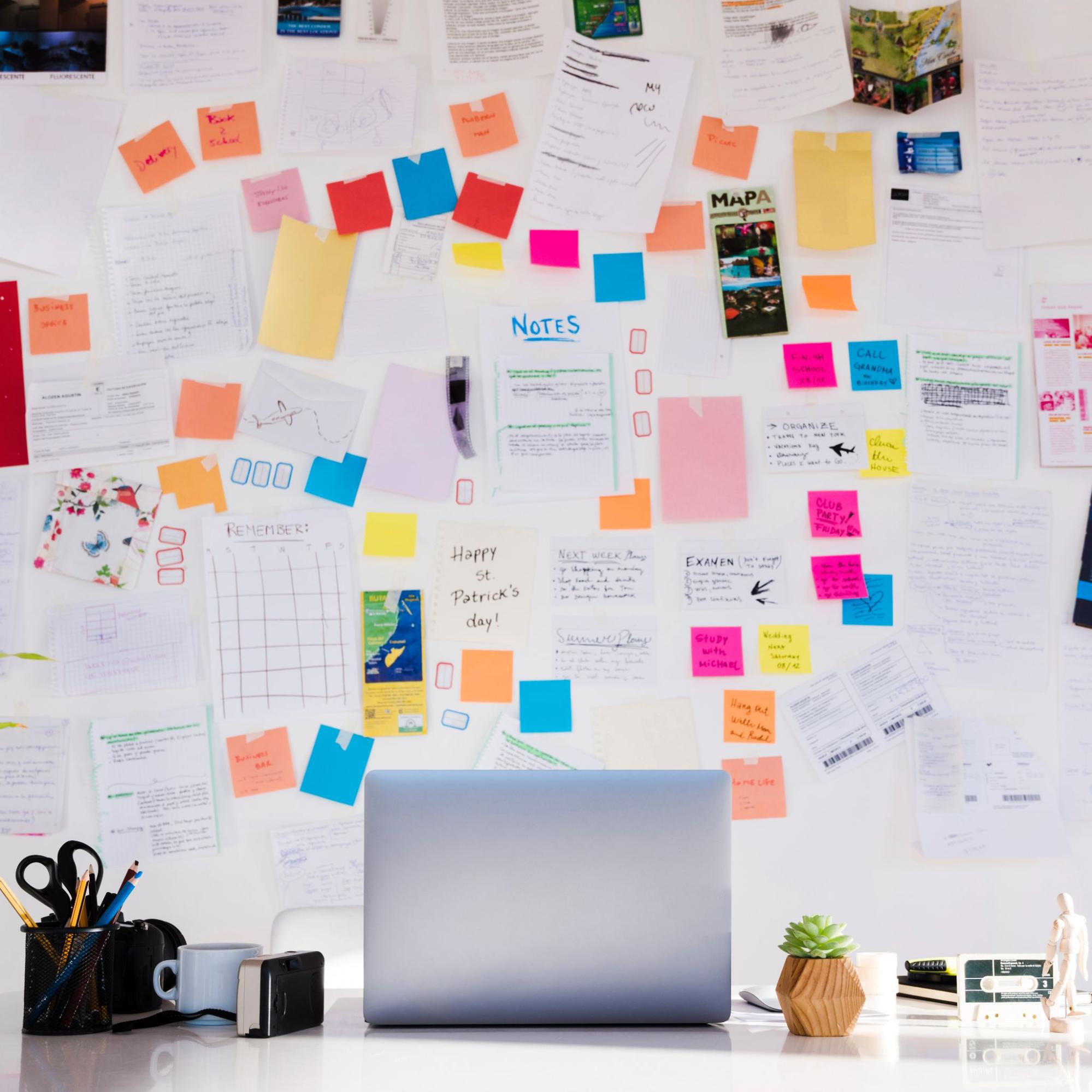 A white wall filled with papers and sticky notes.