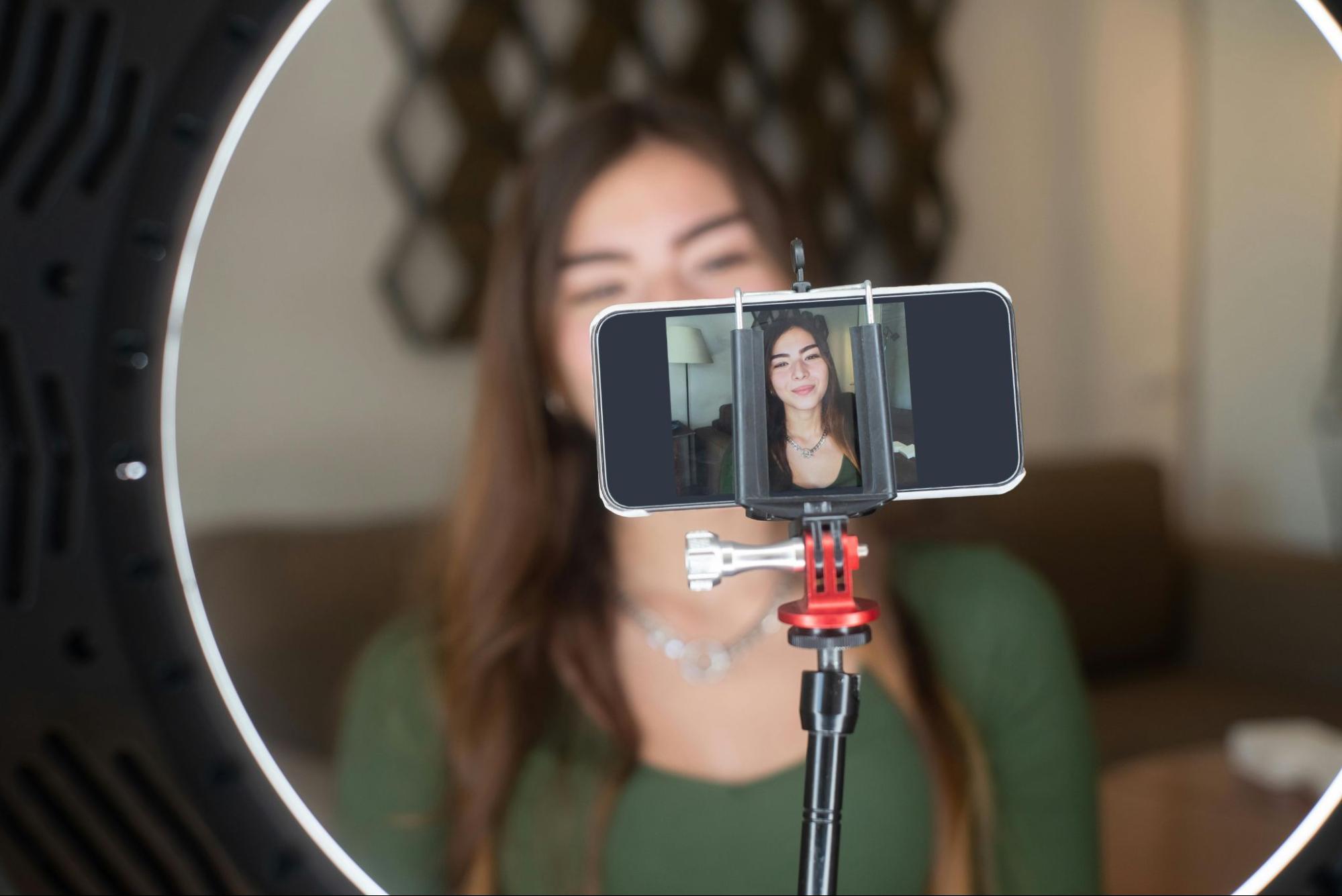 Influencer filming content on a phone on a tripod stand.
