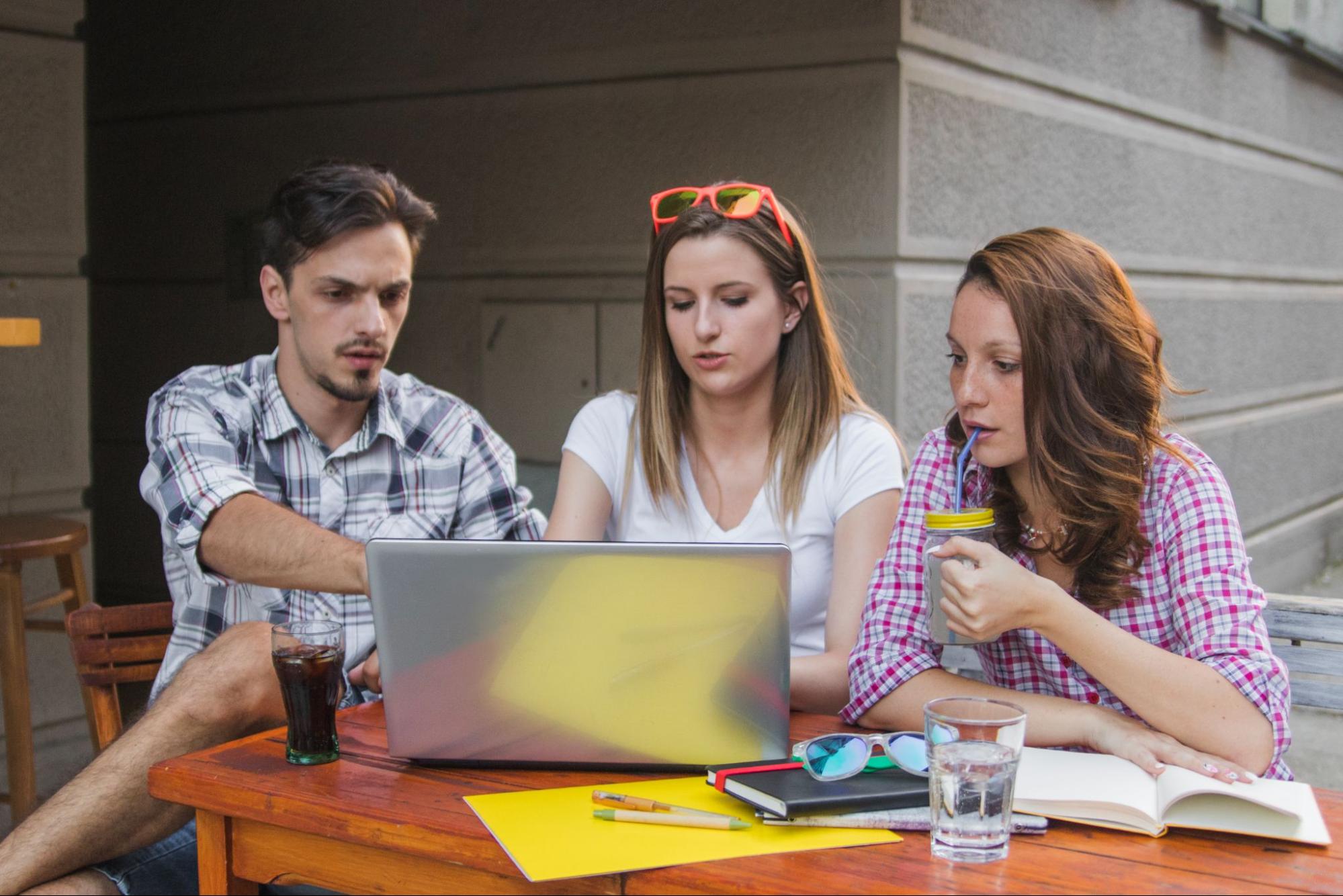 Three people discussing something on a laptop screen.