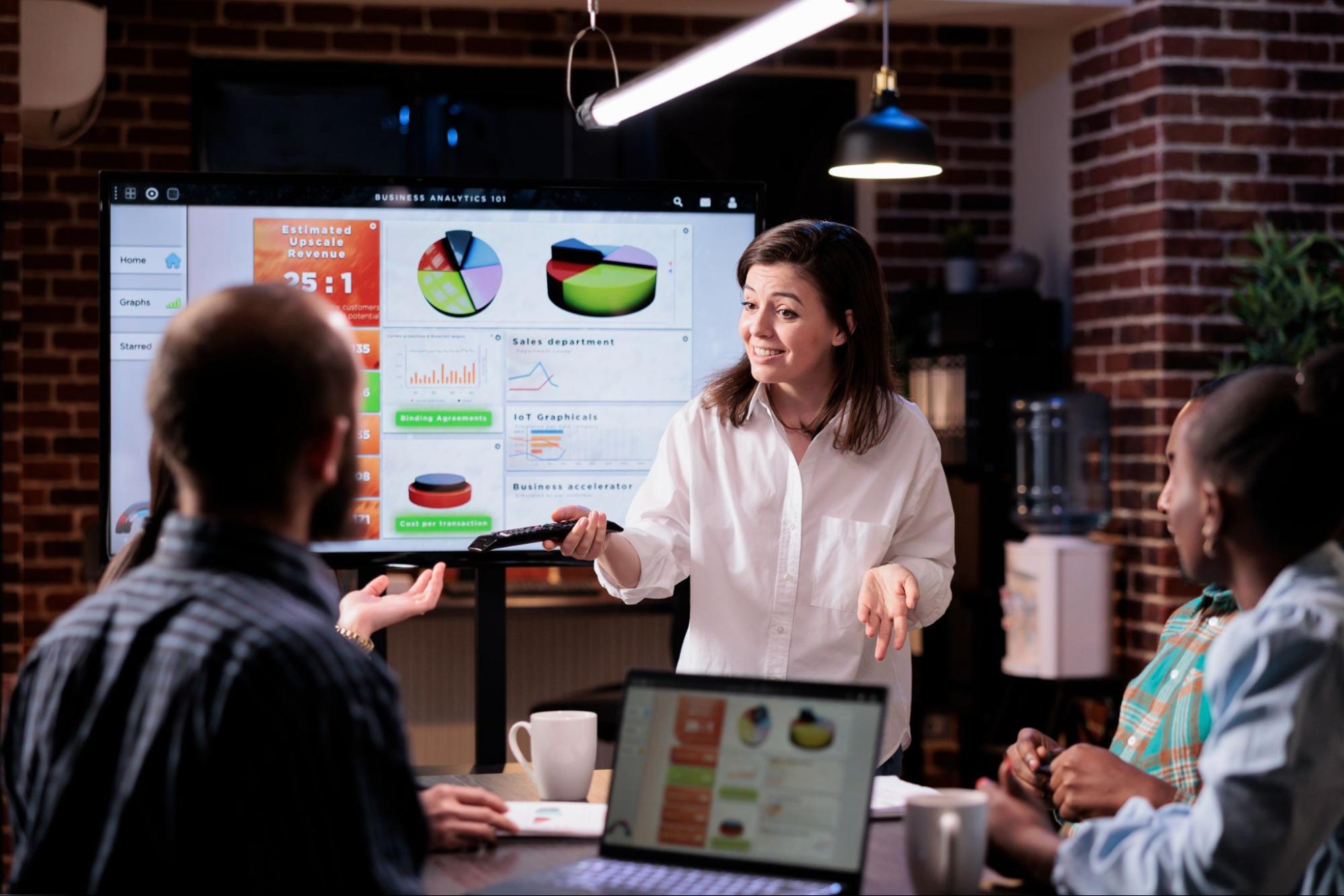 A woman doing a marketing strategy business presentation with a projector behind her.