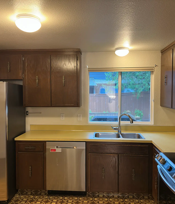 Outdated kitchen with dark wood cabinets, yellow countertops, and dated finishes