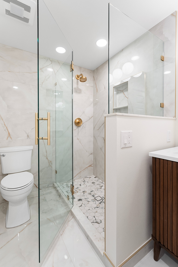 Frameless glass shower panel with a recessed tile niche and modern showerhead in Bothell