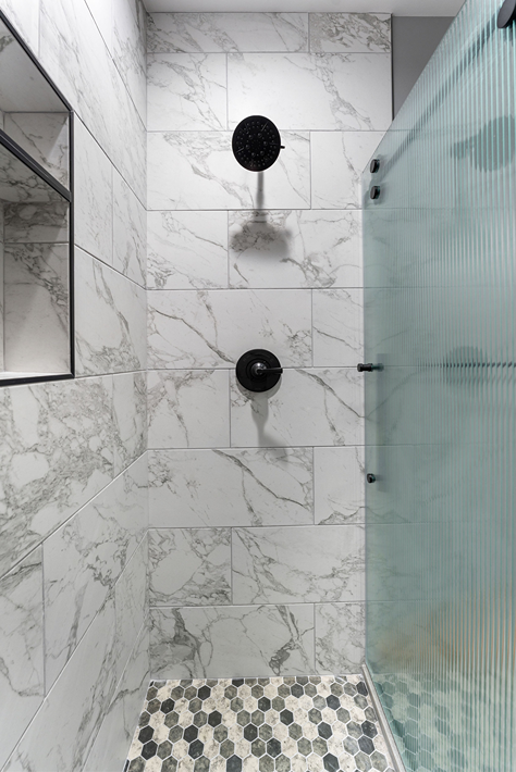 Large format porcelain wall tiles, mosaic flooring and black shower head in a Bothell bathroom

