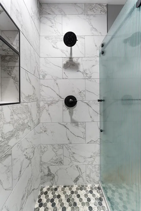 Large format porcelain wall tiles, mosaic flooring and black shower head in a Bothell bathroom
