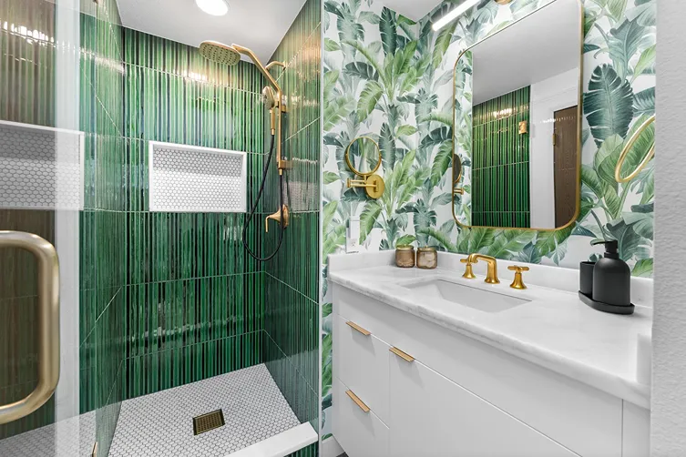 Remodeled walk-in shower featuring vertical green subway tile, gold fixtures, white mosaic floor tile, and a built-in recess niche.