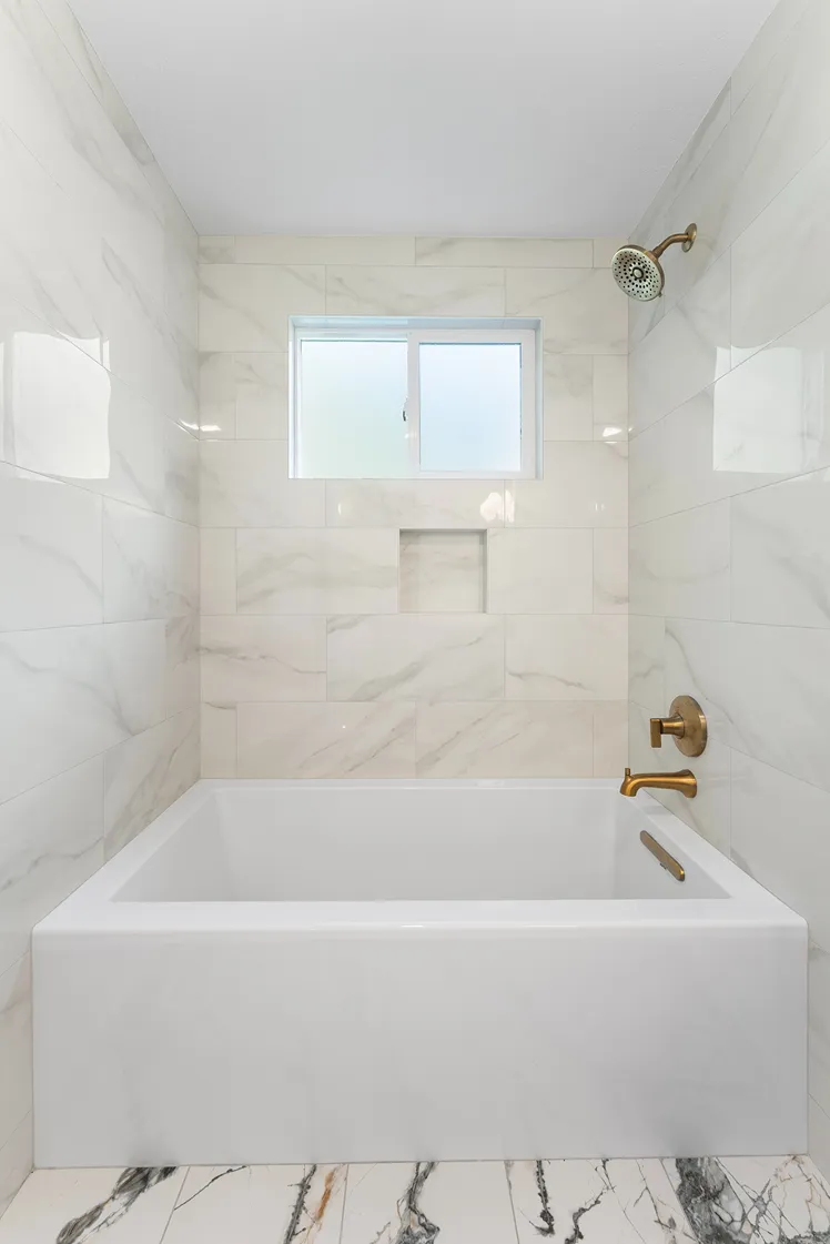 Newly renovated bathroom with freestanding tub and granite wall tiles