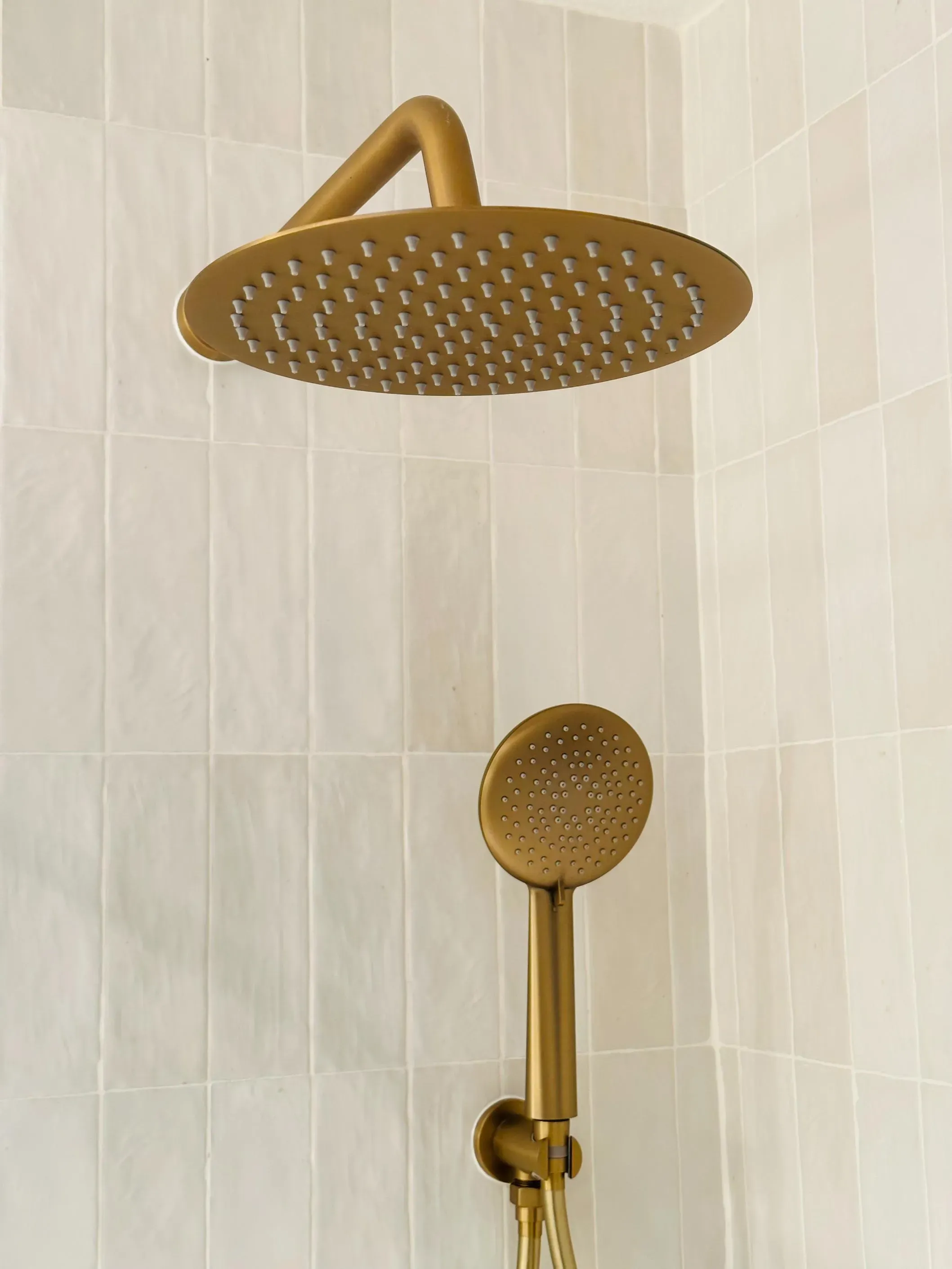 Brass showerhead and hand shower mounted on a tiled wall in Bothell