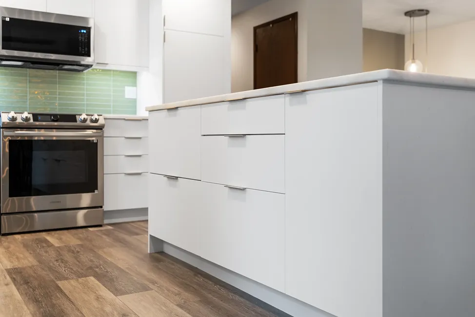 Minimalist flat-panel white painted kitchen cabinets and island drawers with slim brass edge pulls