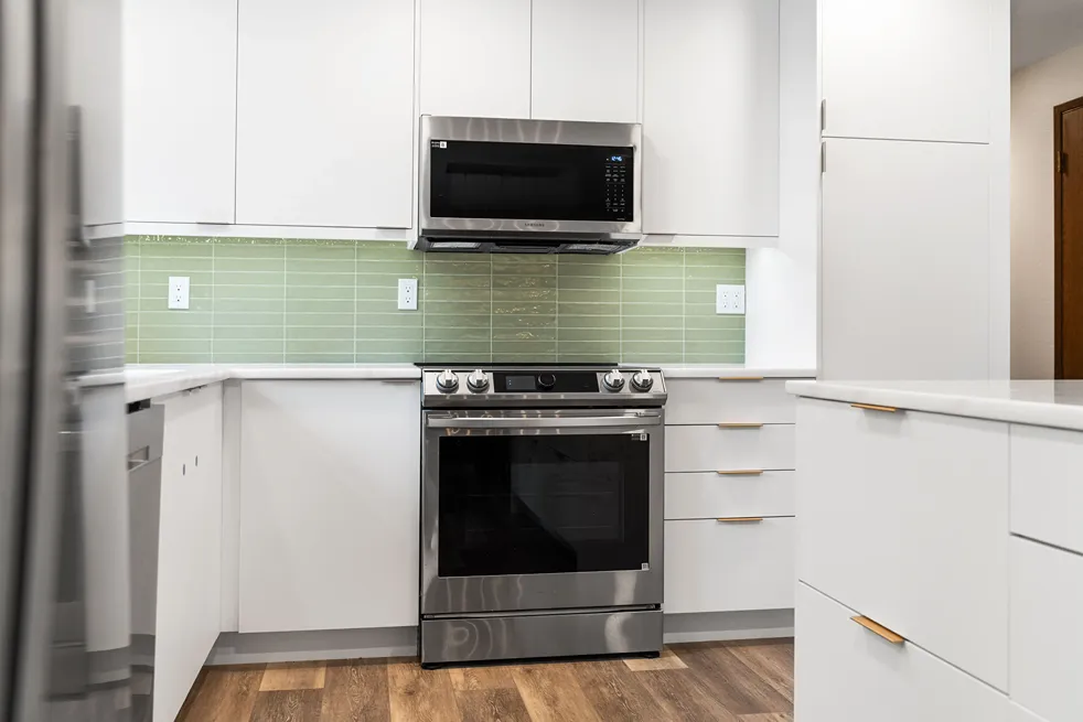 Smooth factory-finish white painted flat-panel kitchen cabinets and drawers with slim brass edge pulls