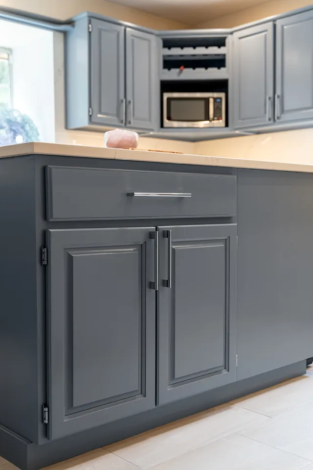 Close-up of slate blue painted cabinet doors and top drawer with sleek metallic handles on a kitchen island.