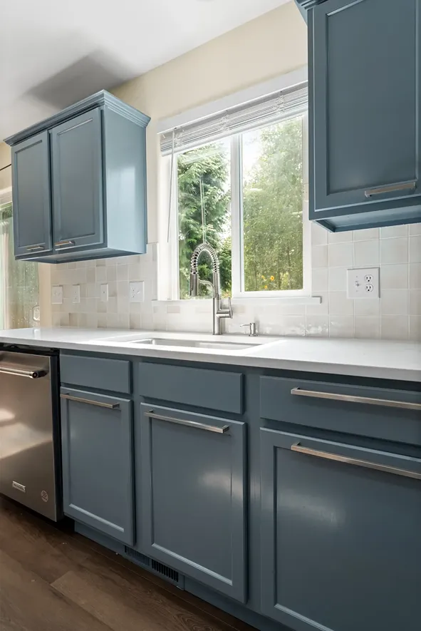 Slate blue painted cabinet doors and drawers with slim silver handles installed along a kitchen counter.