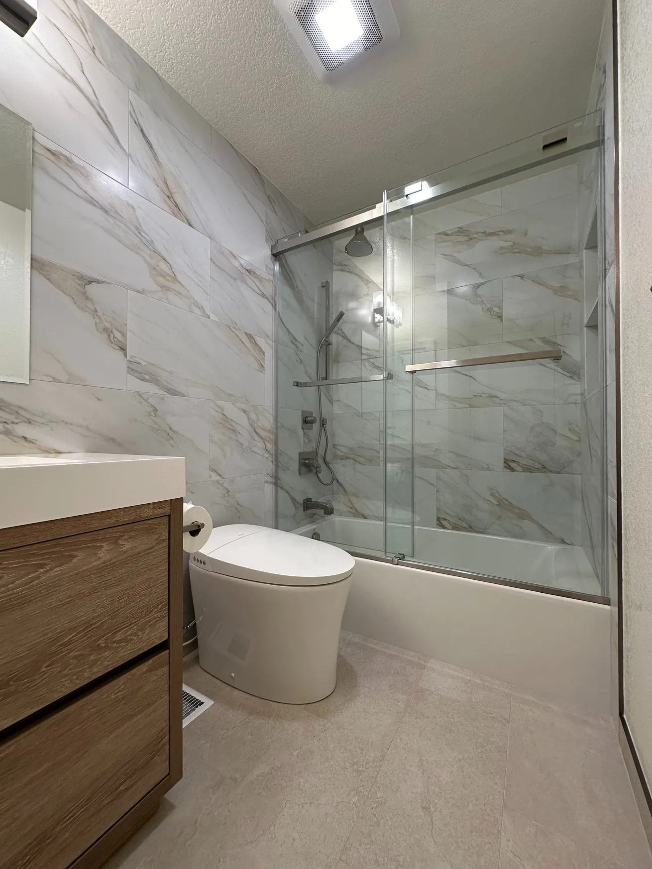 Staggered horizontal marble-pattern wall tiles around a tub-shower