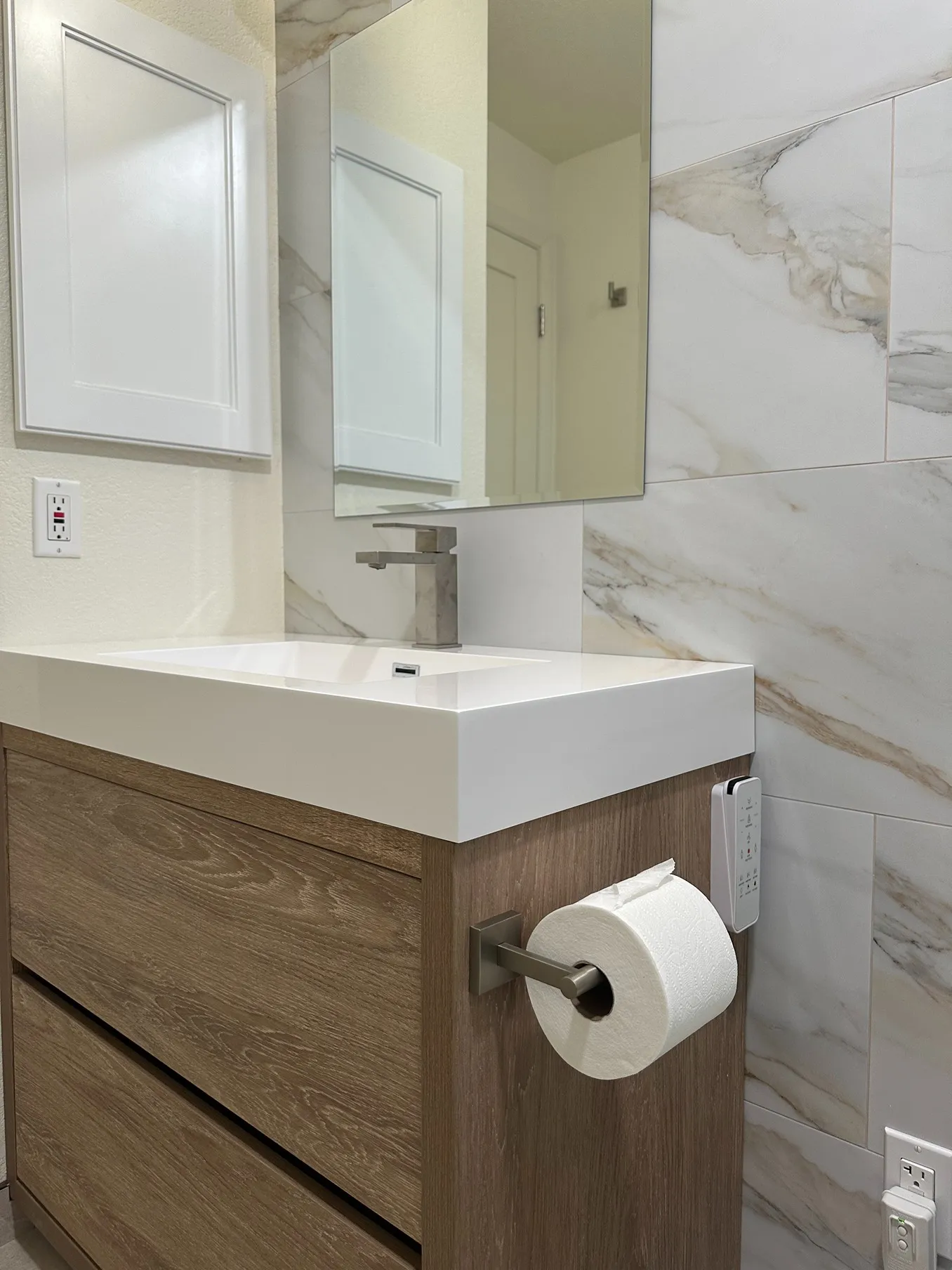 Large white and gold marble-look tiles installed horizontally on the wall behind a bathroom vanity.