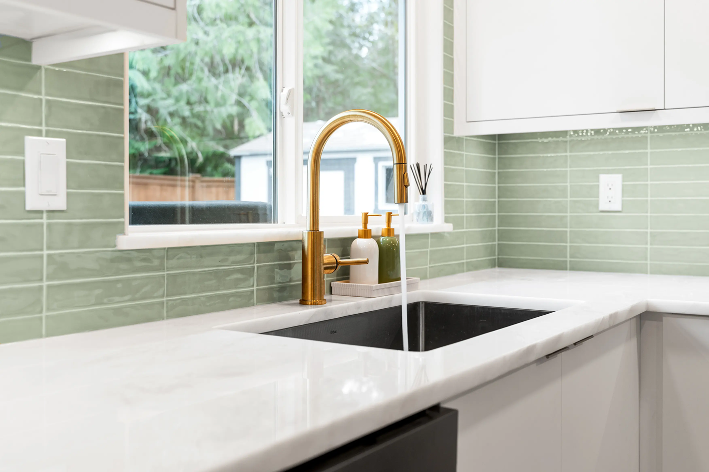 Smooth white marble countertop with an undermount sink set against a green subway tile backsplash.