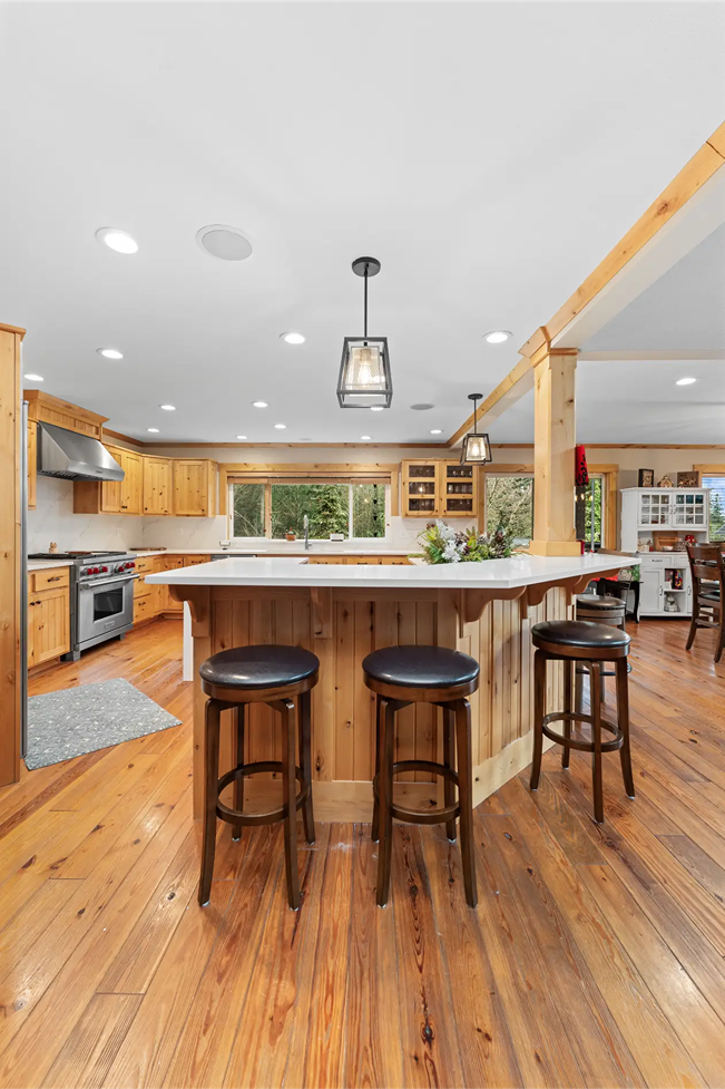 Kitchen breakfast bar island with white quartz countertops and three dark wood bar stools