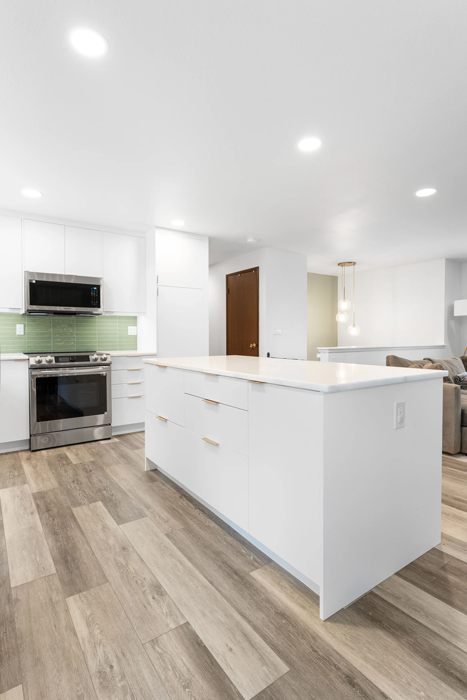 Minimalist white kitchen island with marble-look quartz countertops surrounded by flat-panel white cabinets