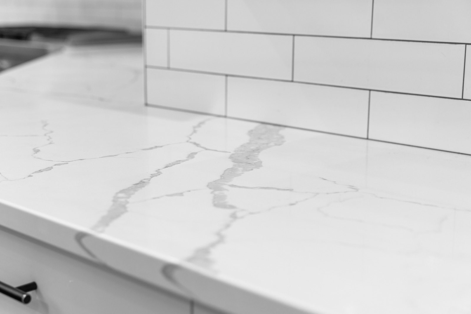 Close-up of a polished white calacatta quartz countertop with subtle grey veining