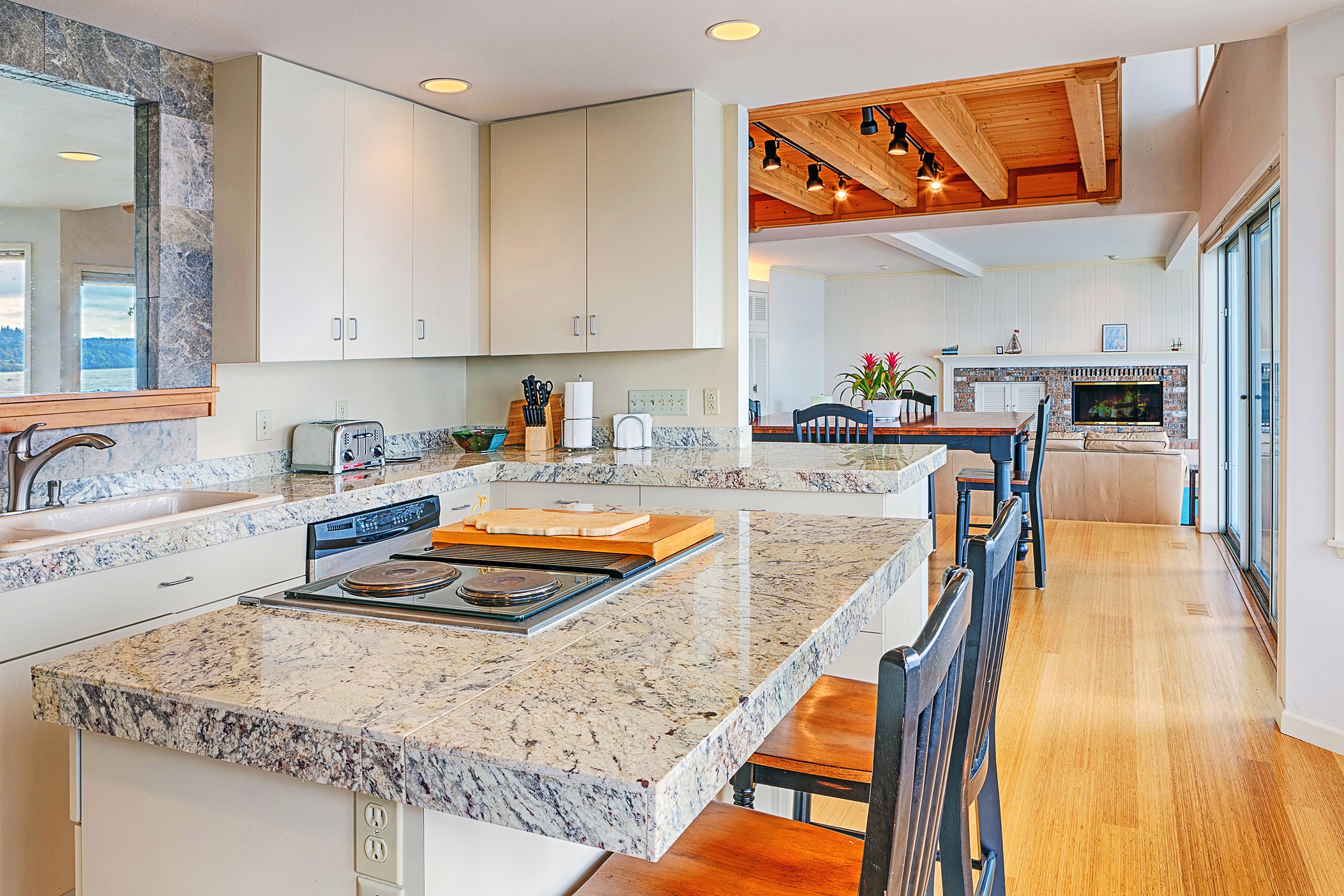 Speckled beige and gray granite countertops fitted on a kitchen island and surrounding counters.