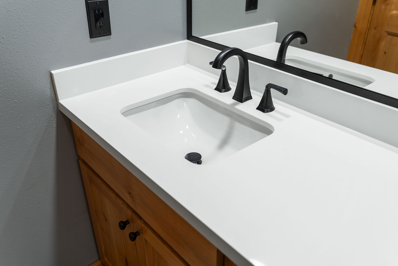 White quartz vanity countertop replacement with an under-mount sink and matte black faucet installed on a wooden vanity.