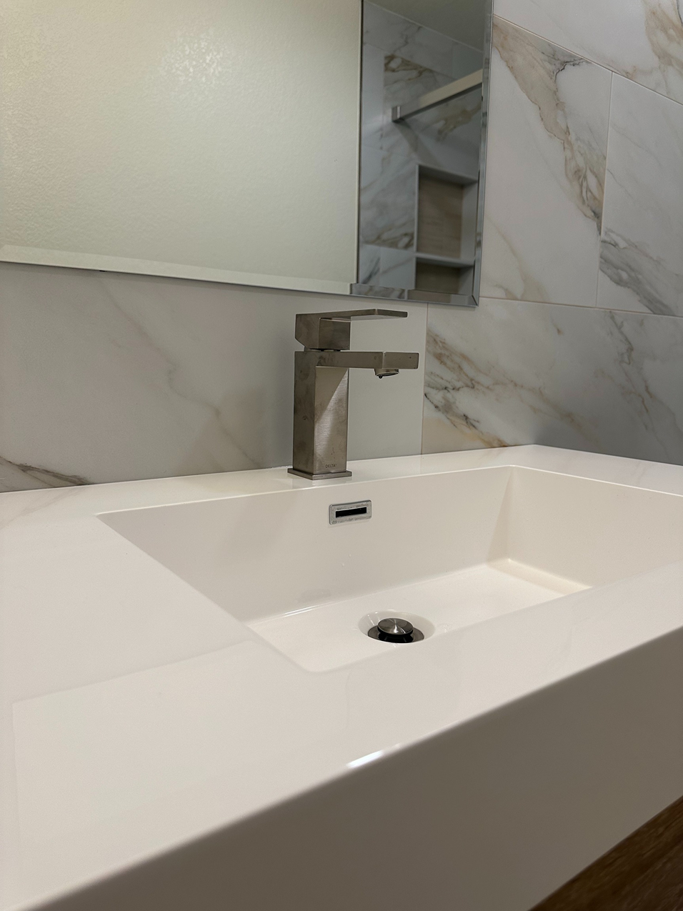 Integrated solid white countertop featuring an angular, sloped basin sink