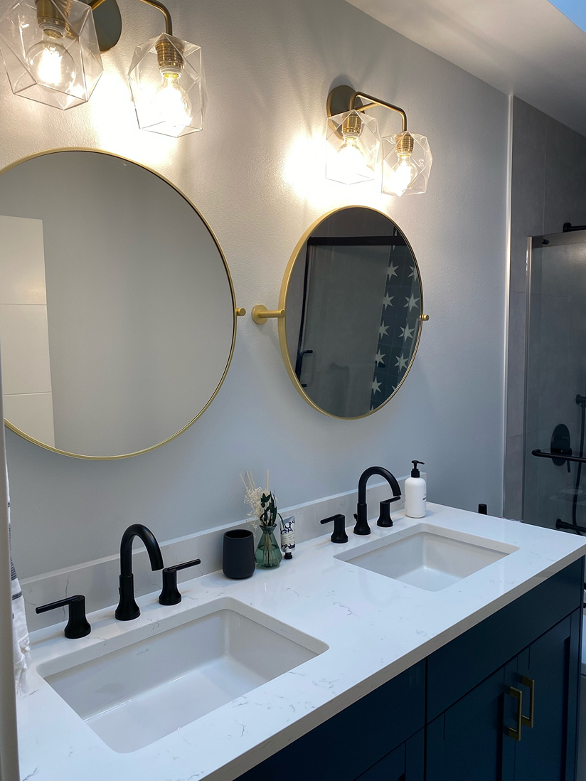 White marble-patterned quartz double-sink vanity top featuring rectangular under-mount sinks and dual black arched faucets 