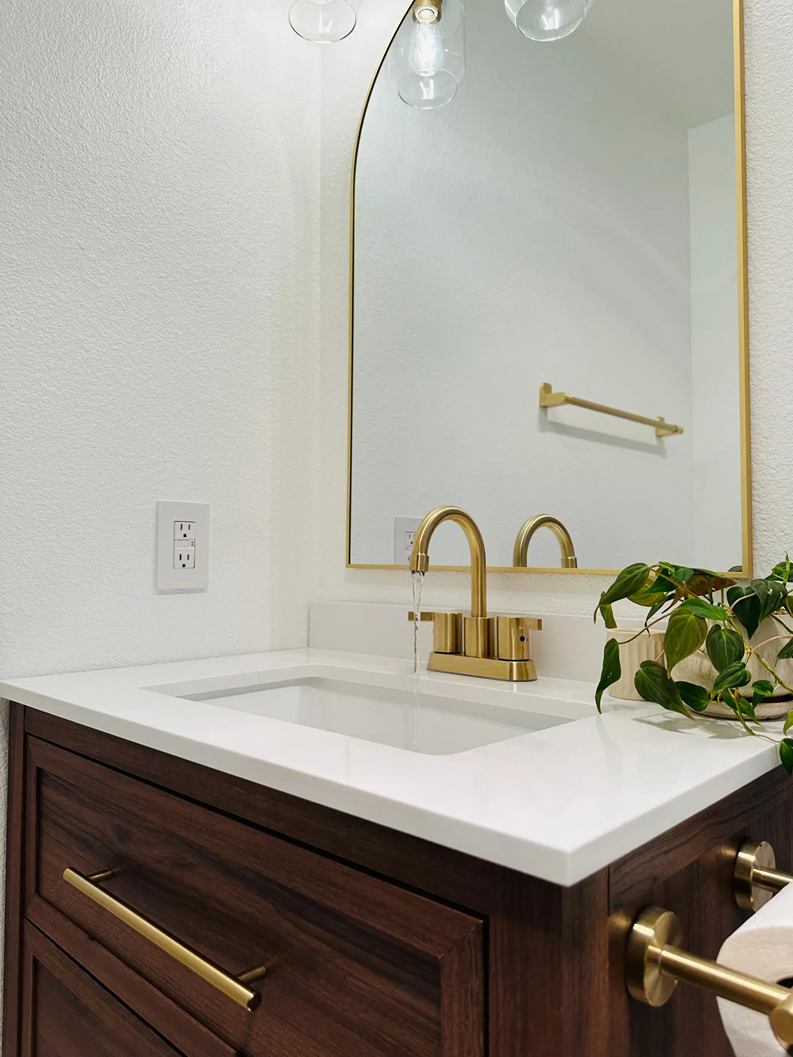 White vanity countertop with an under-mount rectangular sink and brushed brass gooseneck faucet
