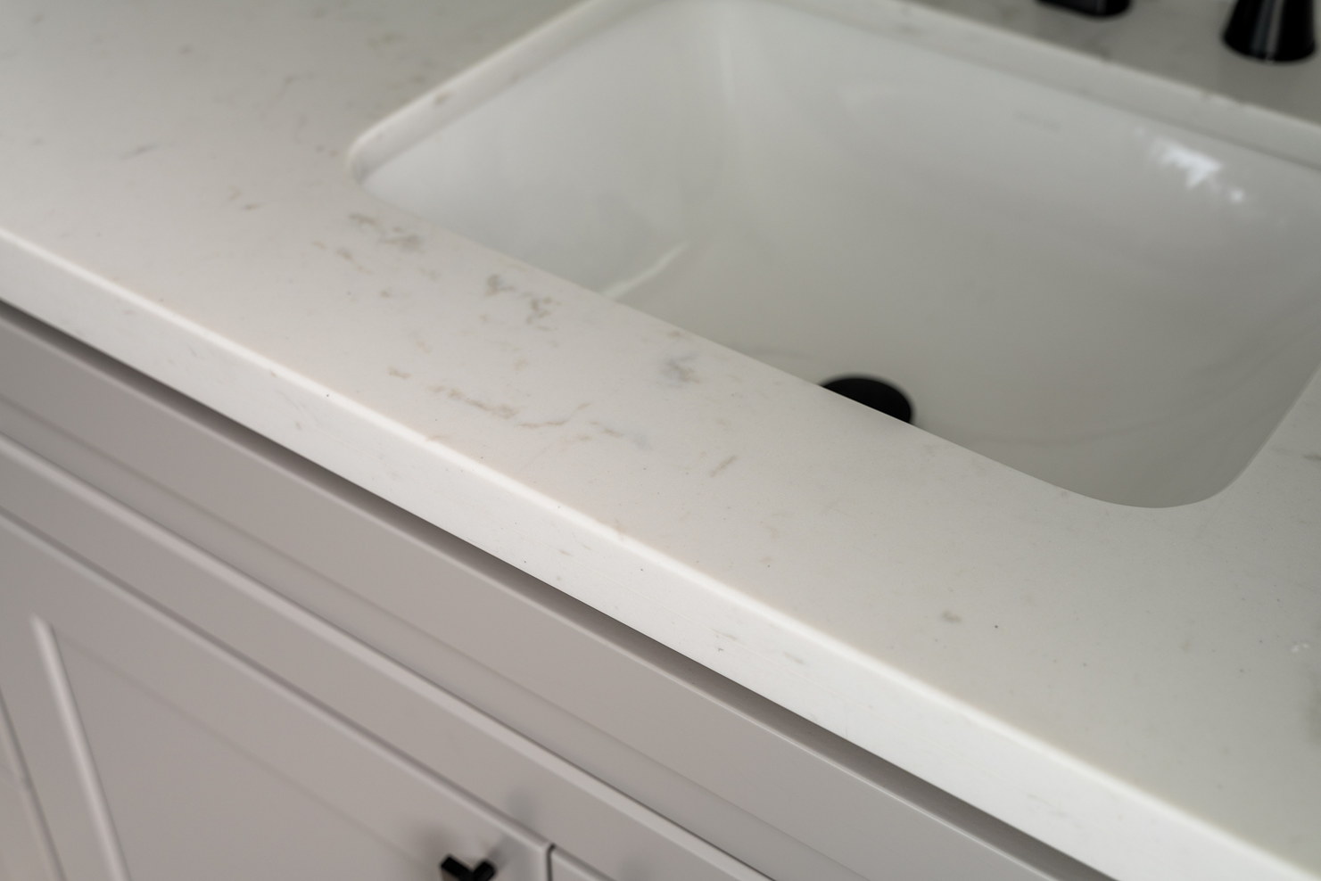 Close-up of a light gray, subtle-veined quartz countertop with a clean under-mount sink