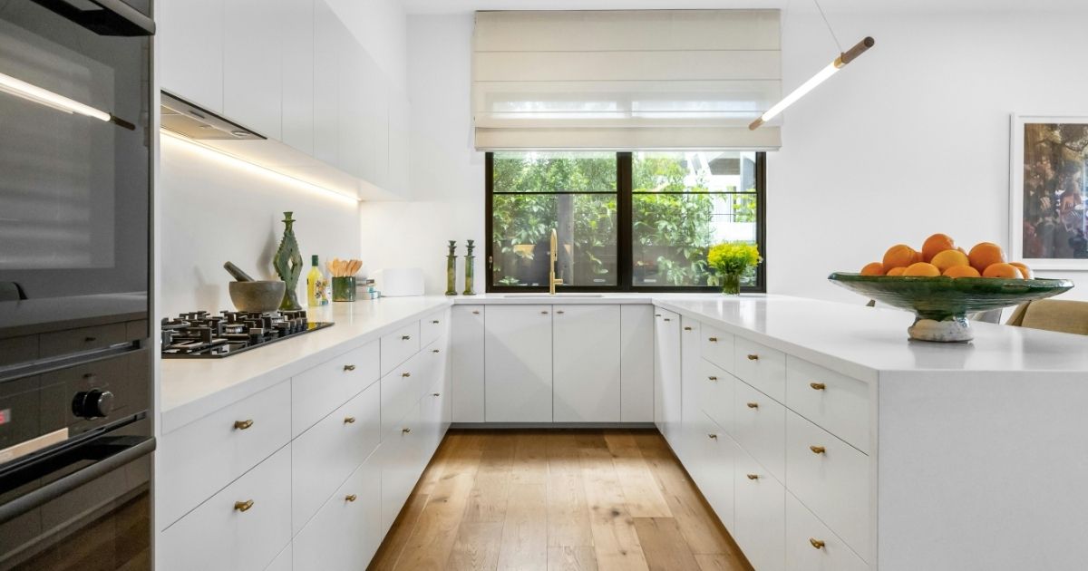 A modern kitchen with white cabinets and wooden floors
