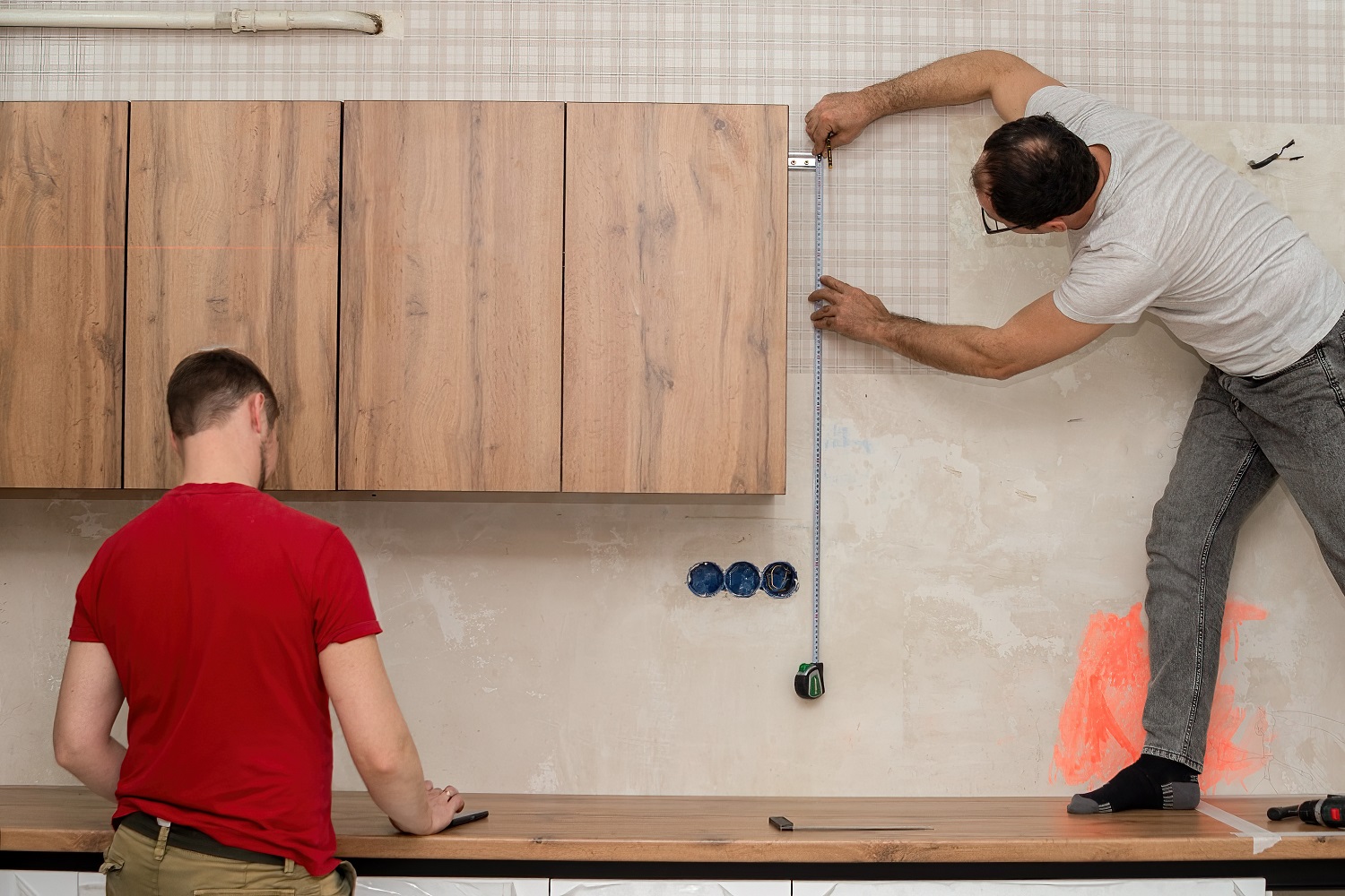 Contractor installing a wooden cabinet in a kitchen 