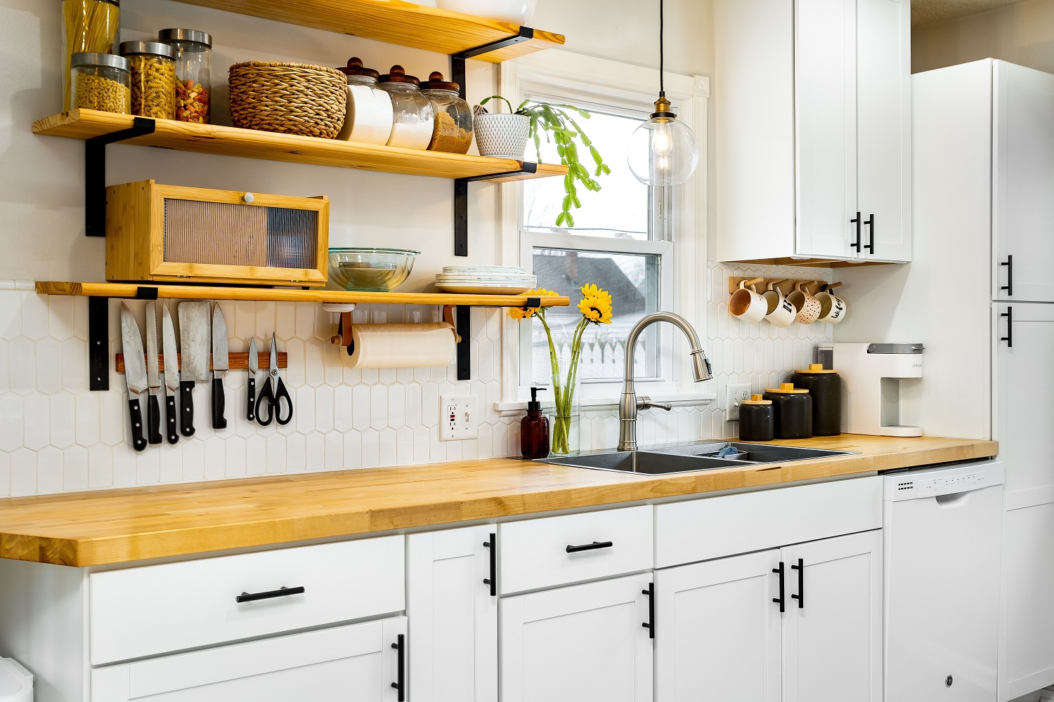 Interior view of a bright kitchen with white cabinets and shelves filled with spices and cuttlery 