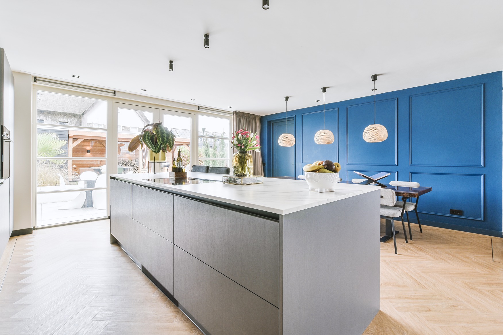 A kitchen island built in a Bothell home with blue wooden walls and modern dining set