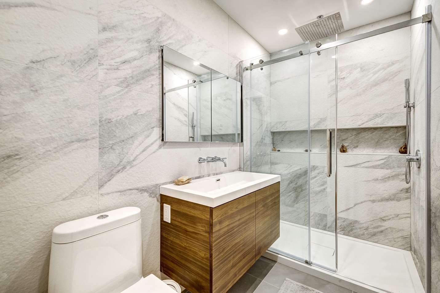 A walk-in shower in Bothell with stylish tiled walls, sink and vanity mirror