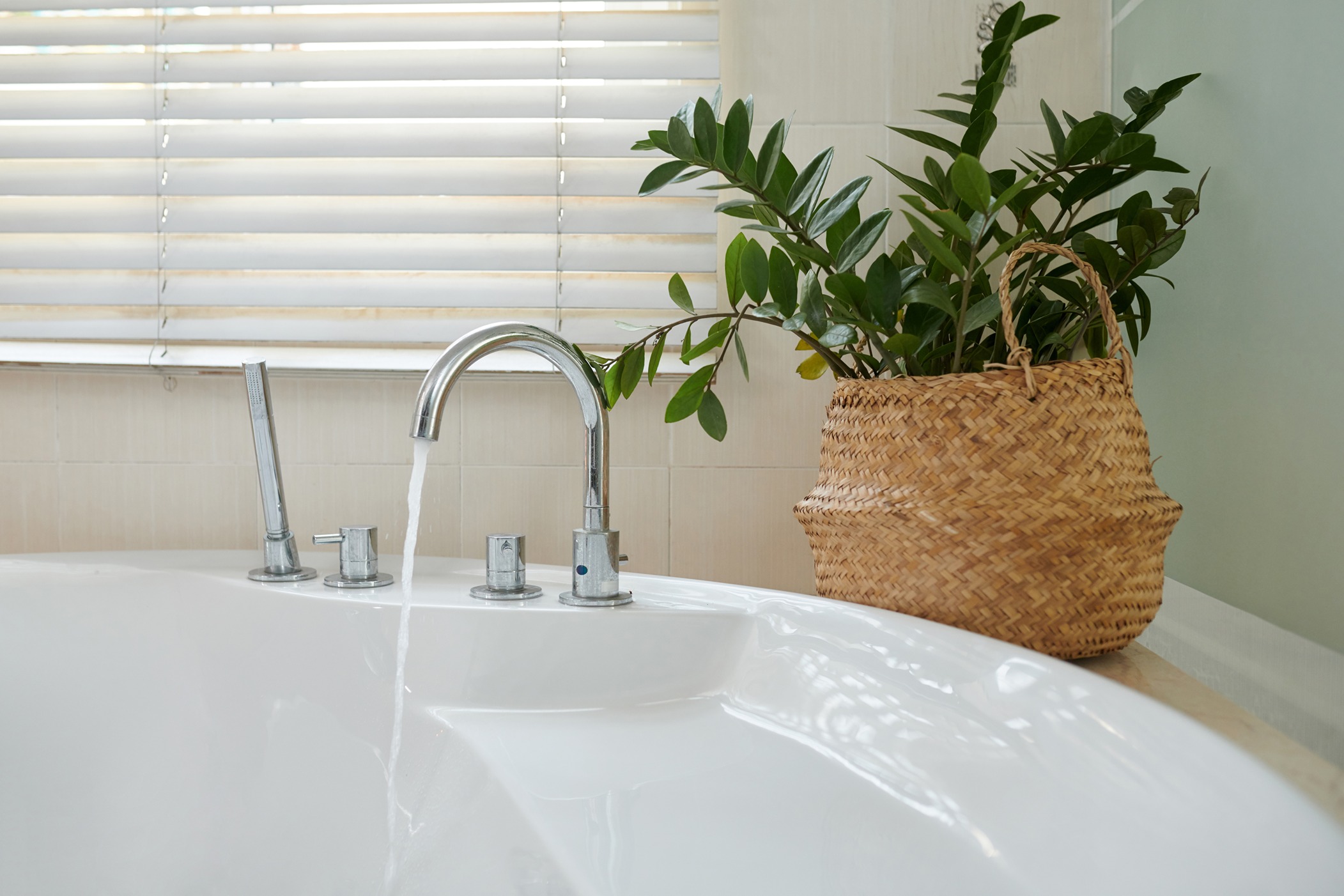 A bathtub in a Bothell home with the faucet turned on and a plant in a basket