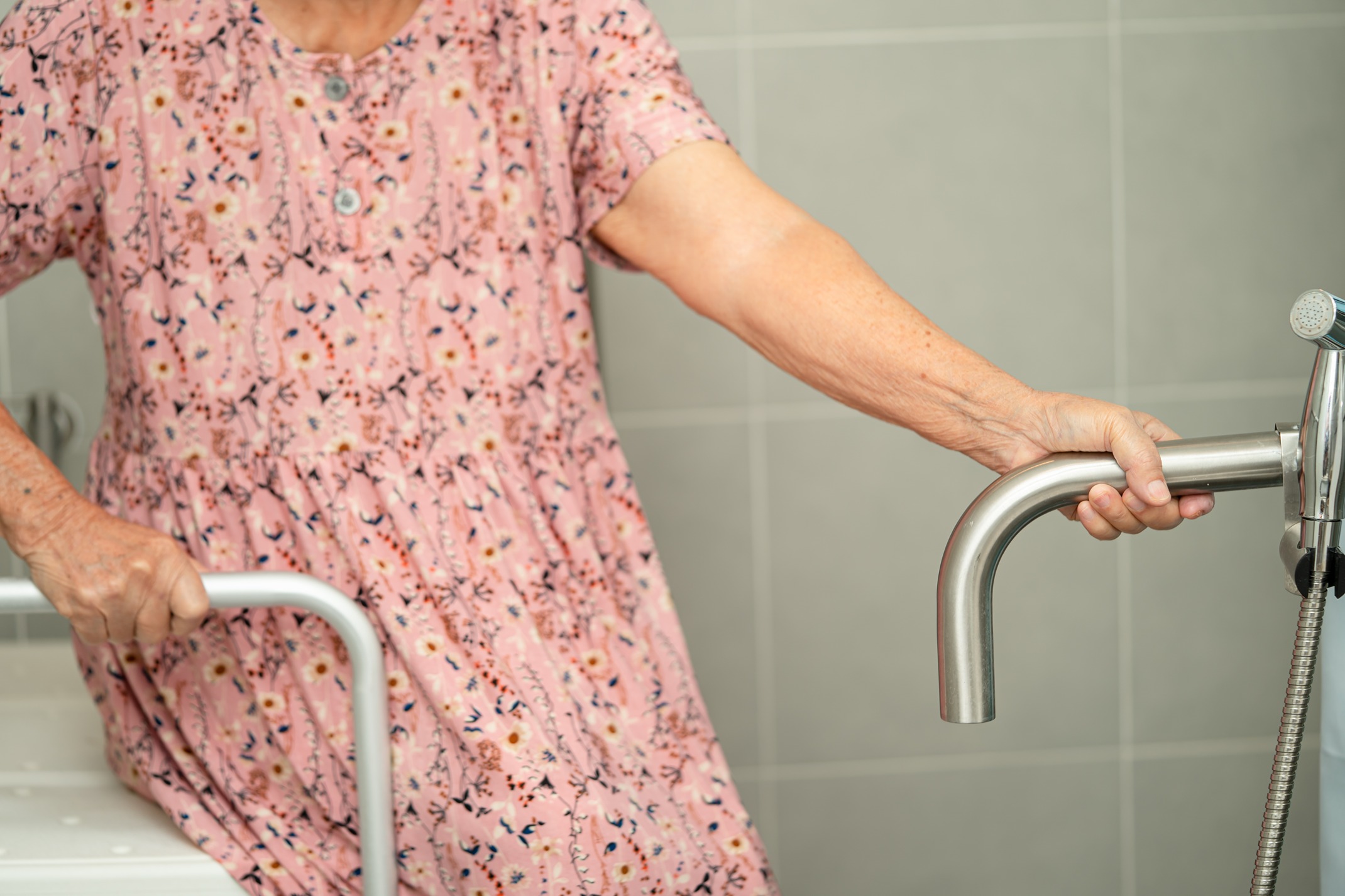 An elderly person preparing to be seated in a walk-in tub