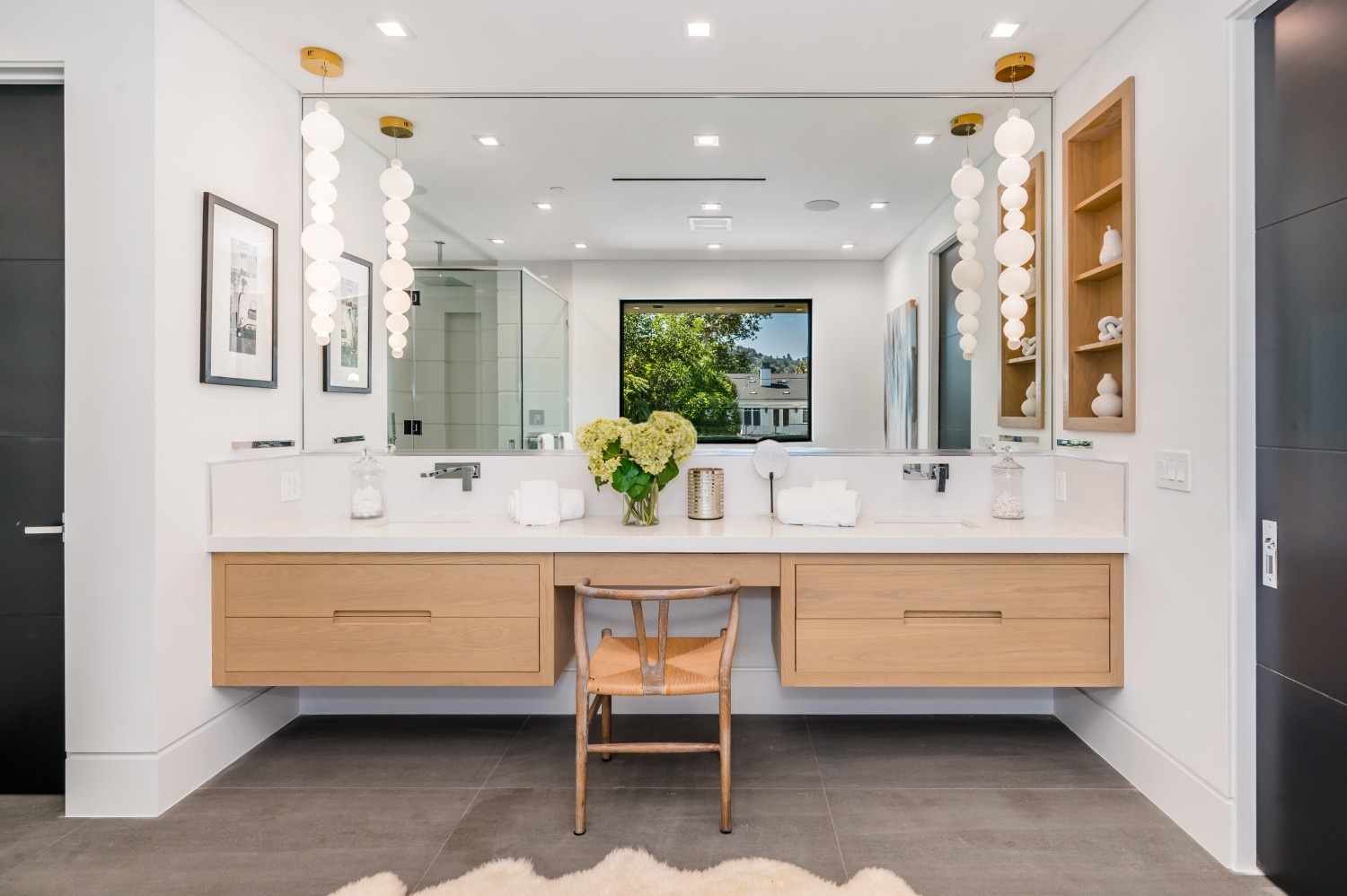 Floating light wood double vanity with a built-in seated makeup area, an example of custom bathroom cabinetry in a Bothell home